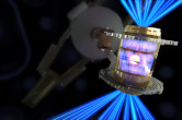 The National Ignition Facility's 192 laser beams shine into a gold can. It glows hot and emits x-rays that implode a fuel capsule at its center (artist's conception)